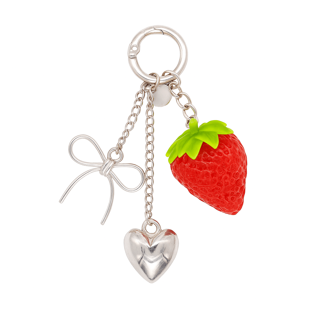 Charm de aleación metálica con tres colgantes: fresa de resina, lazo en forma de alambre y corazón metálico. Incluye una anilla circular resistente para aplicar el adaptador universal y utilizarlo en el móvil o como llavero. 
